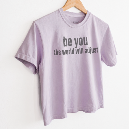 Women’s Be You The World Will Adjust graphic tee featuring an empowering self love message, with a relaxed mid length fit perfect for positive everyday style. Shop Fineish