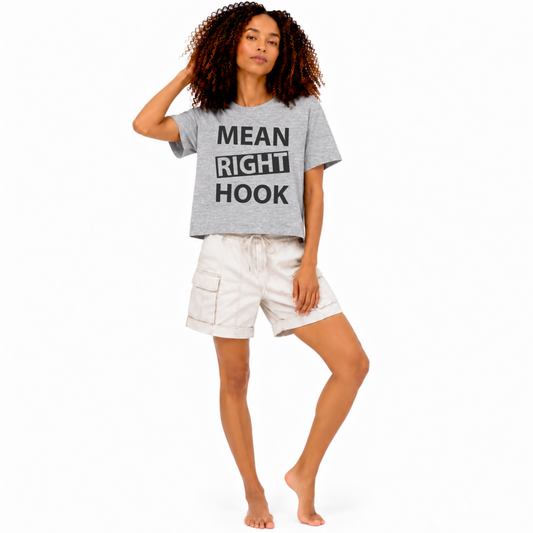Woman wearing an athletic heather grey mid-length boxy crop T-shirt featuring the words “Mean Right Hook.”