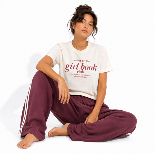 Women's vintage garment-dyed book lover t-shirt styled for a cozy bookstore or coffee shop, featuring the "Member of the Girl Book Club" graphic.