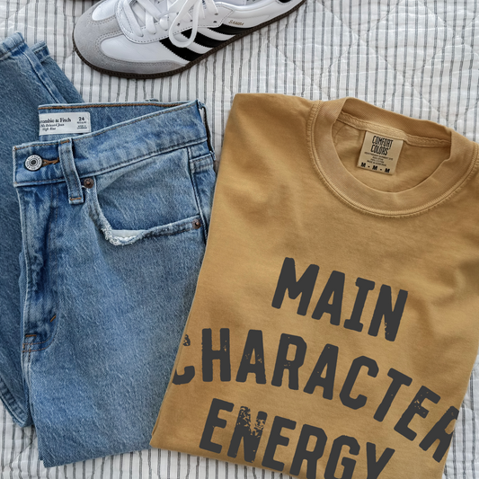 Unisex retro Main Character Energy graphic t-shirt styled for trendy streetwear and confident everyday outfit. Aesthetic statement shirt in mustard ivory gray blue crimson and white for viral social media fashion looks