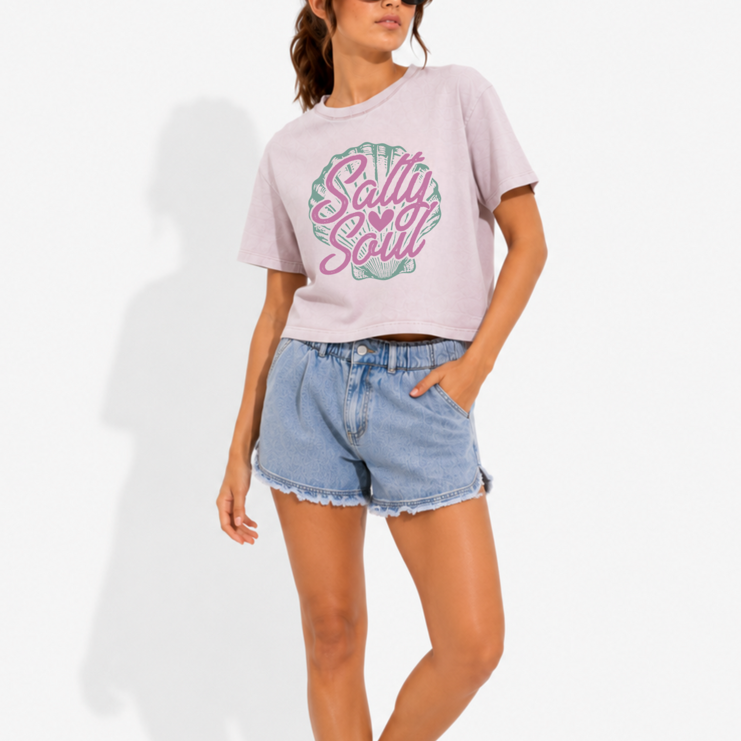 Woman wearing a washed garment-dyed t-shirt featuring the phrase "Salty Soul" with a vintage coastal-inspired graphic, offering a relaxed beach lifestyle look.