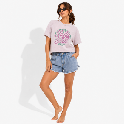 Women's vintage-style garment-dyed t-shirt with the Salty Soul graphic, styled for a coastal beach setting with a relaxed summer aesthetic.