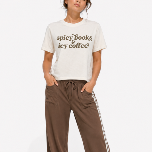 Woman wearing a washed garment-dyed t-shirt with a "Spicy Books & Icy Coffee" graphic, perfect for romance readers, book lovers, and iced coffee fans.