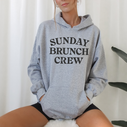Unisex Sunday Brunch Club graphic hoodie styled for cozy fall brunch outfit. Soft fleece pullover in white pink gray and sand for relaxed weekend fashion